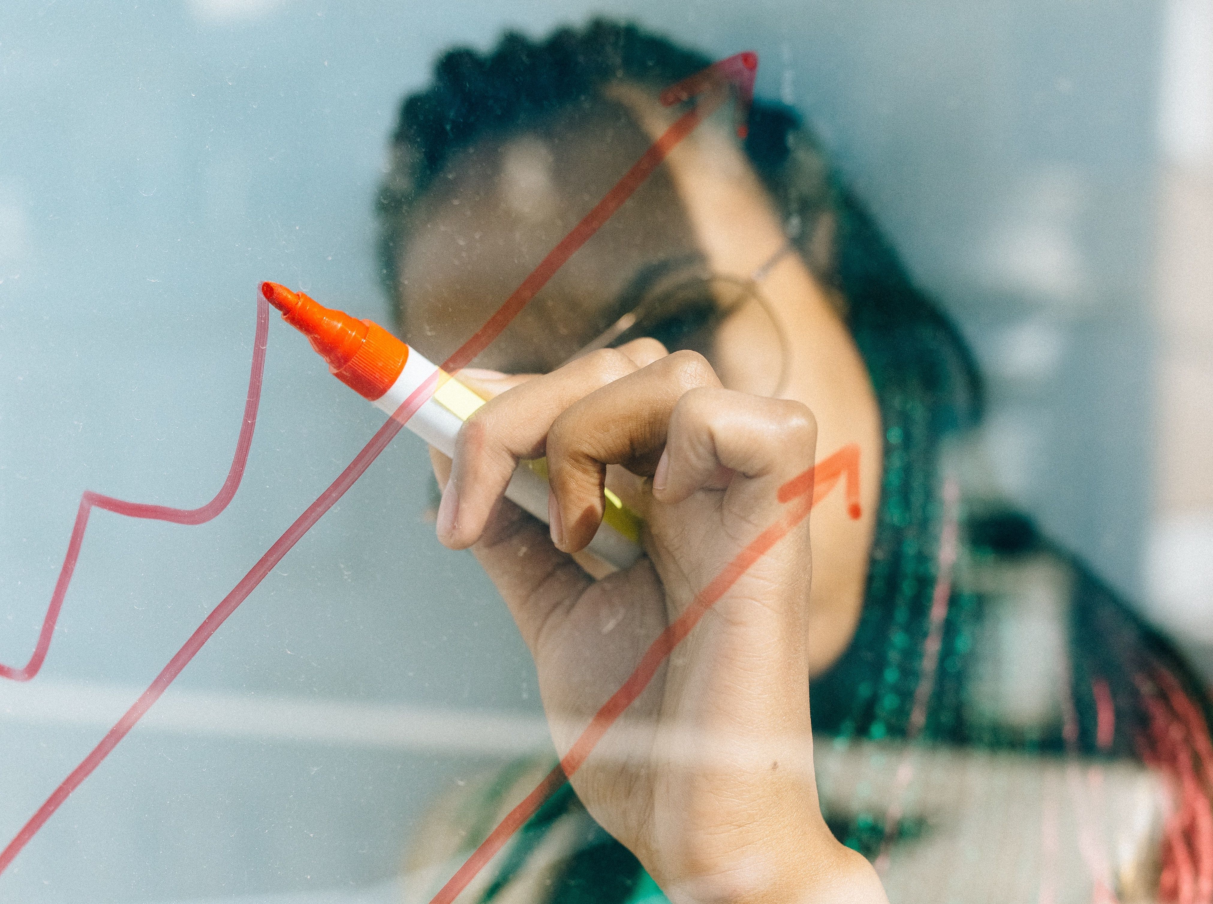 Black woman drawing a graph on a whiteboard